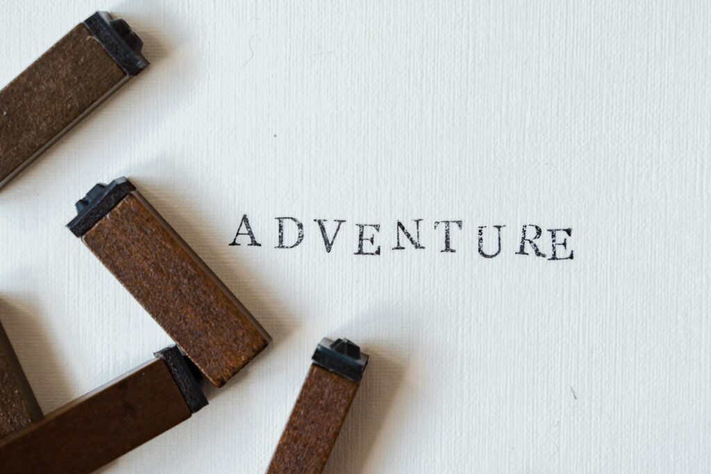 Wooden stamps form the word 'Adventure' on white textured canvas.
