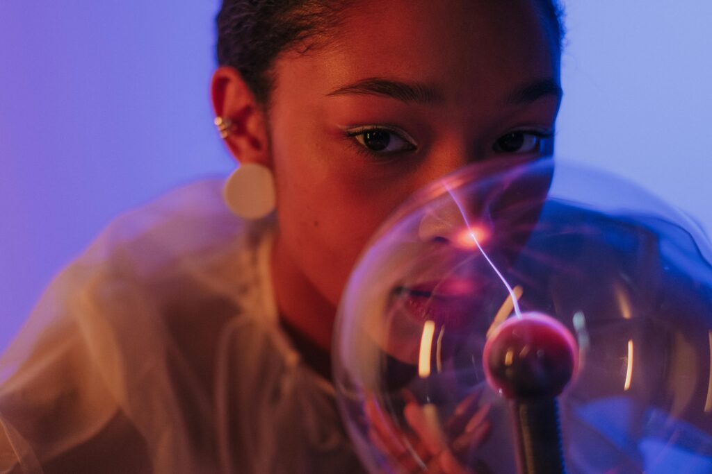 A creative portrait featuring a woman interacting with a plasma ball, creating an electrifying visual effect.